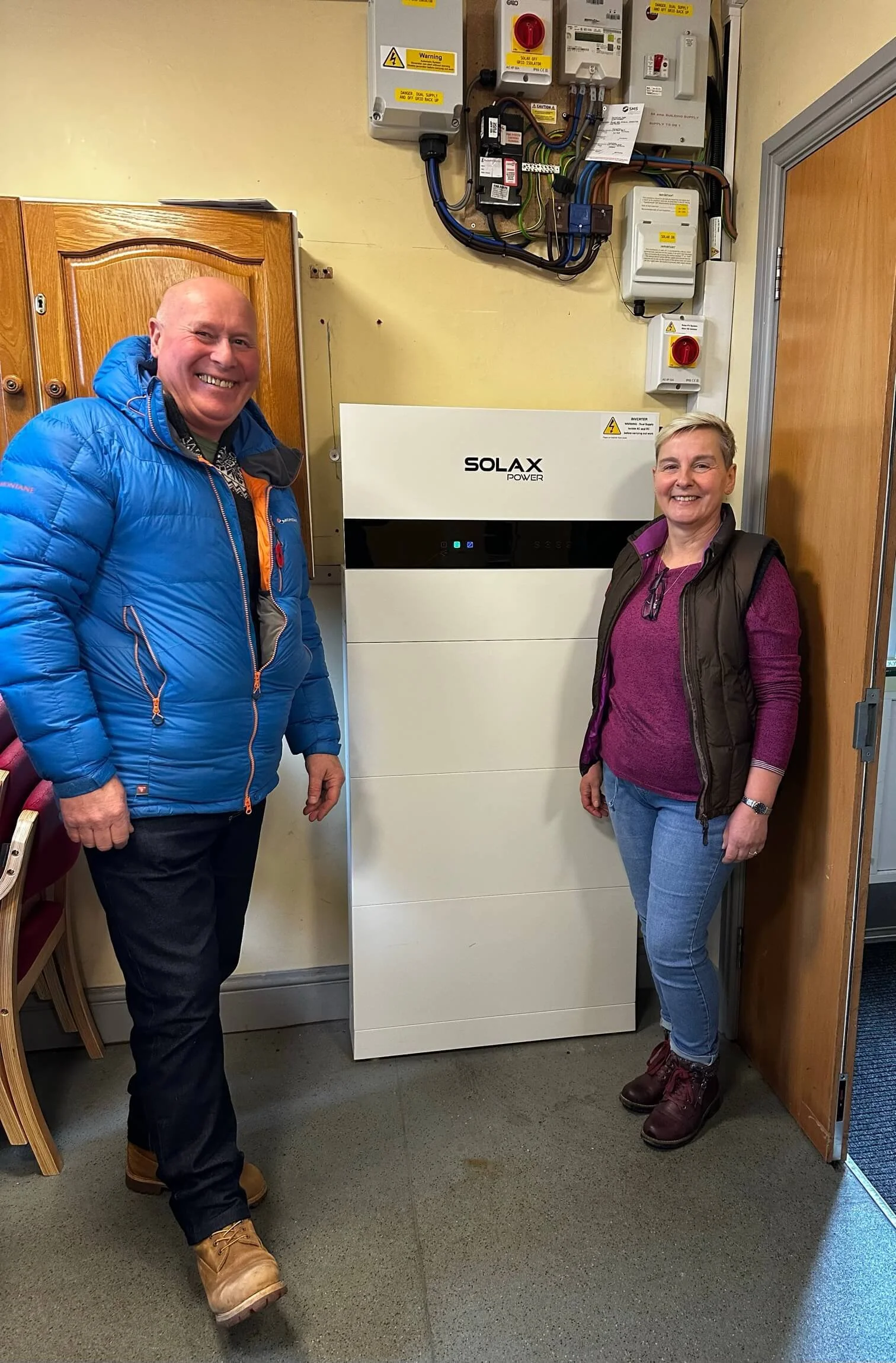 Happy customers stood next to their solar battery at the village hall