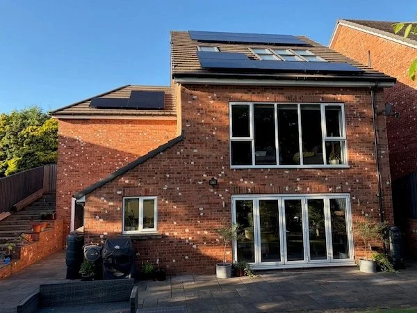 Red-brick detached house with solar panels installed on the roof and extension, Manchester