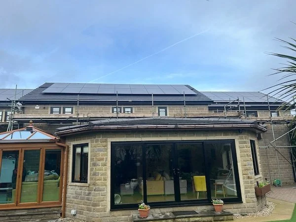 Stone detached house with solar panels installed on the roof and a glass extension, Wakefield