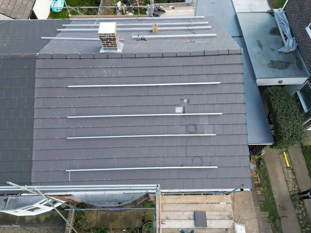 Aerial view of a residential roof during solar panel installation, showing mounting rails fitted across the roof ready for an east-west solar panel array.