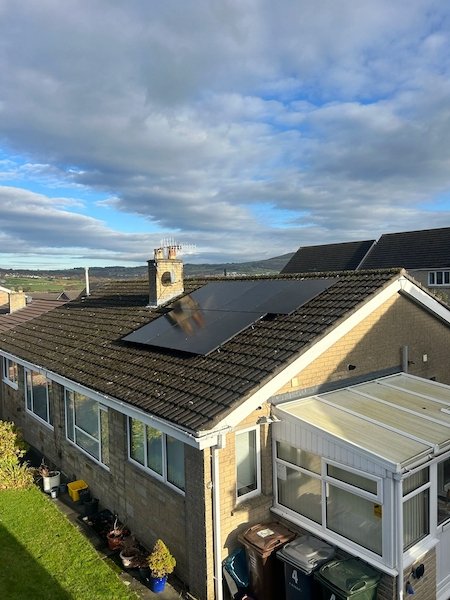 Stone bungalow with solar panels installed on the roof and a conservatory, Keighley