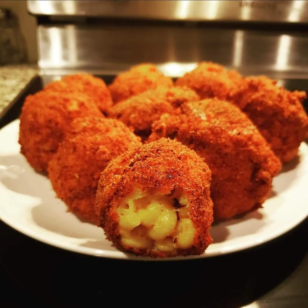 Plate of fried cheese balls with one cut open showing melted cheese inside.