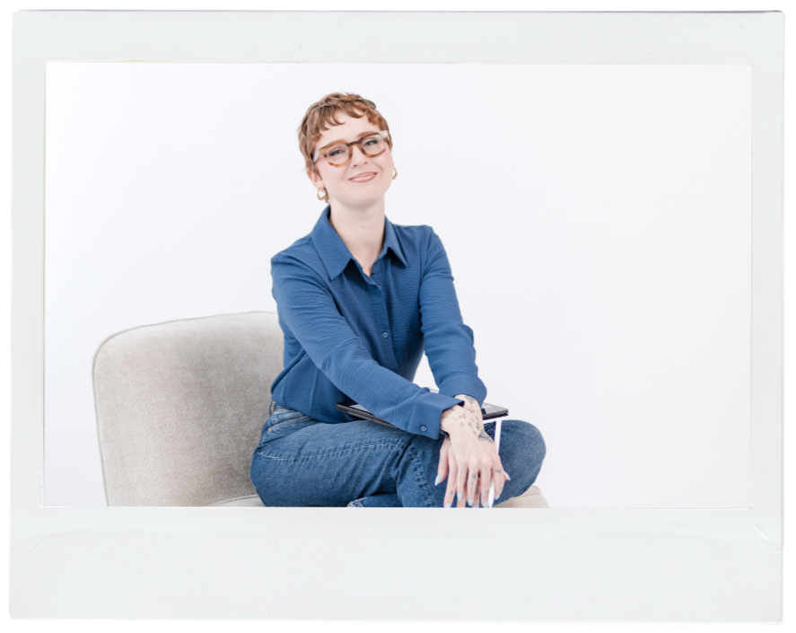 woman in glasses and blue shirt sitting on a chair smiling