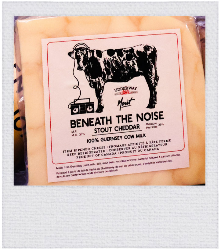 Package of Beneath the Noise Stout Cheddar cheese with a hand-drawn cow wearing headphones drawn by Back Pocket Marketing made for The Udderway Artisan Cheese Co.
