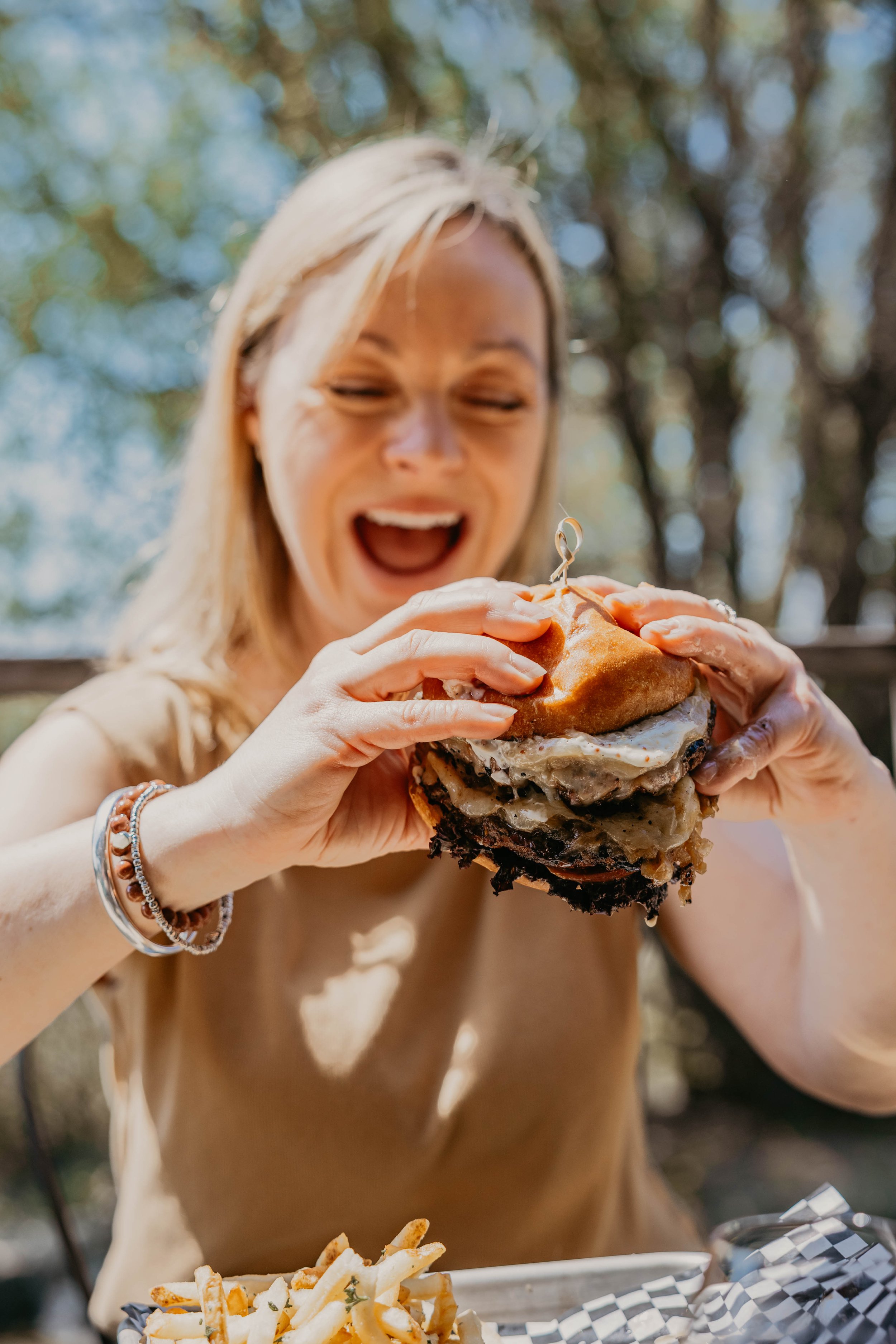 woman smiling as she is about to take a bit of a burger