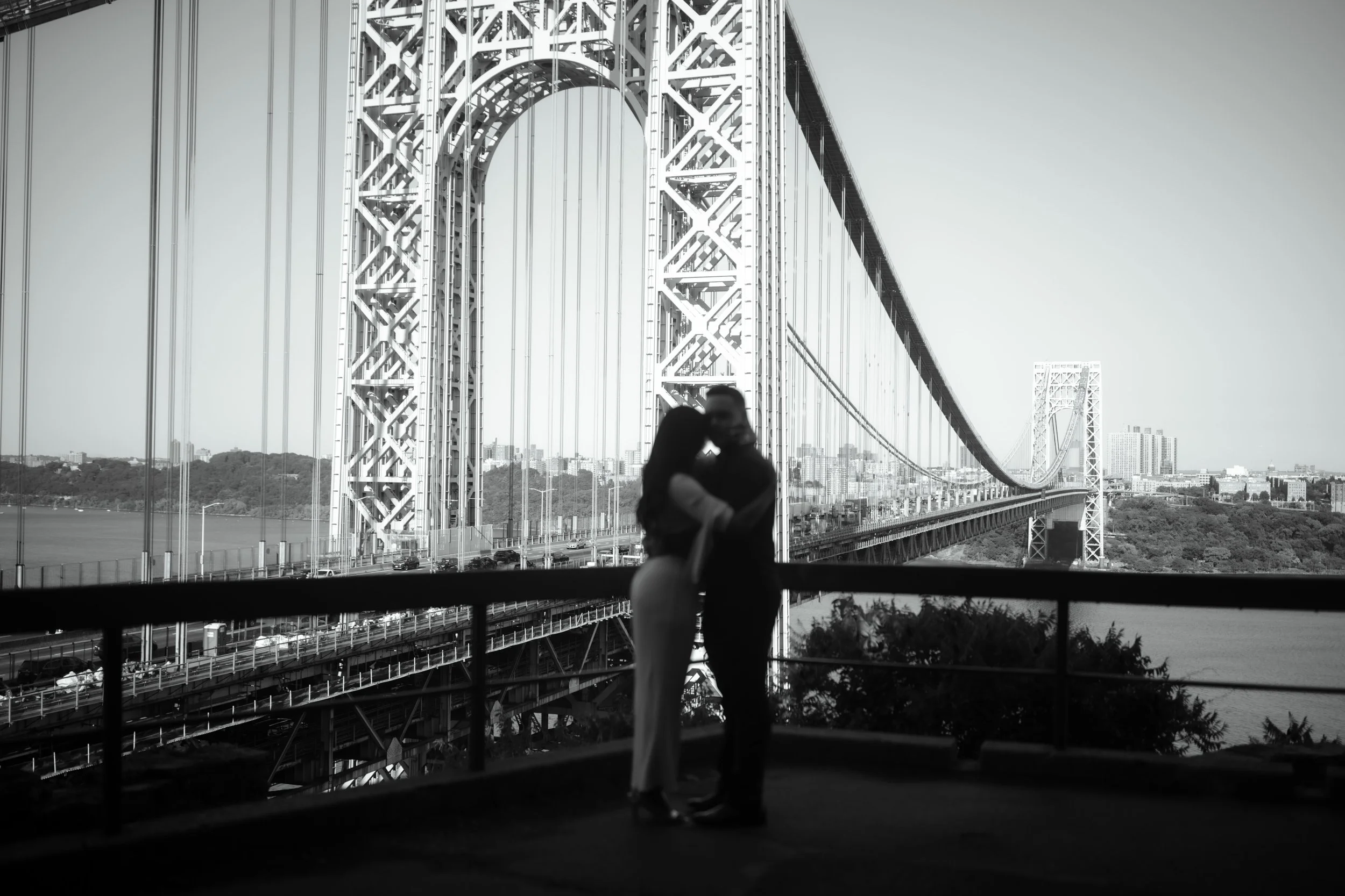 Silhouette of a couple embracing and about to kiss with the Bay Bridge in the background.