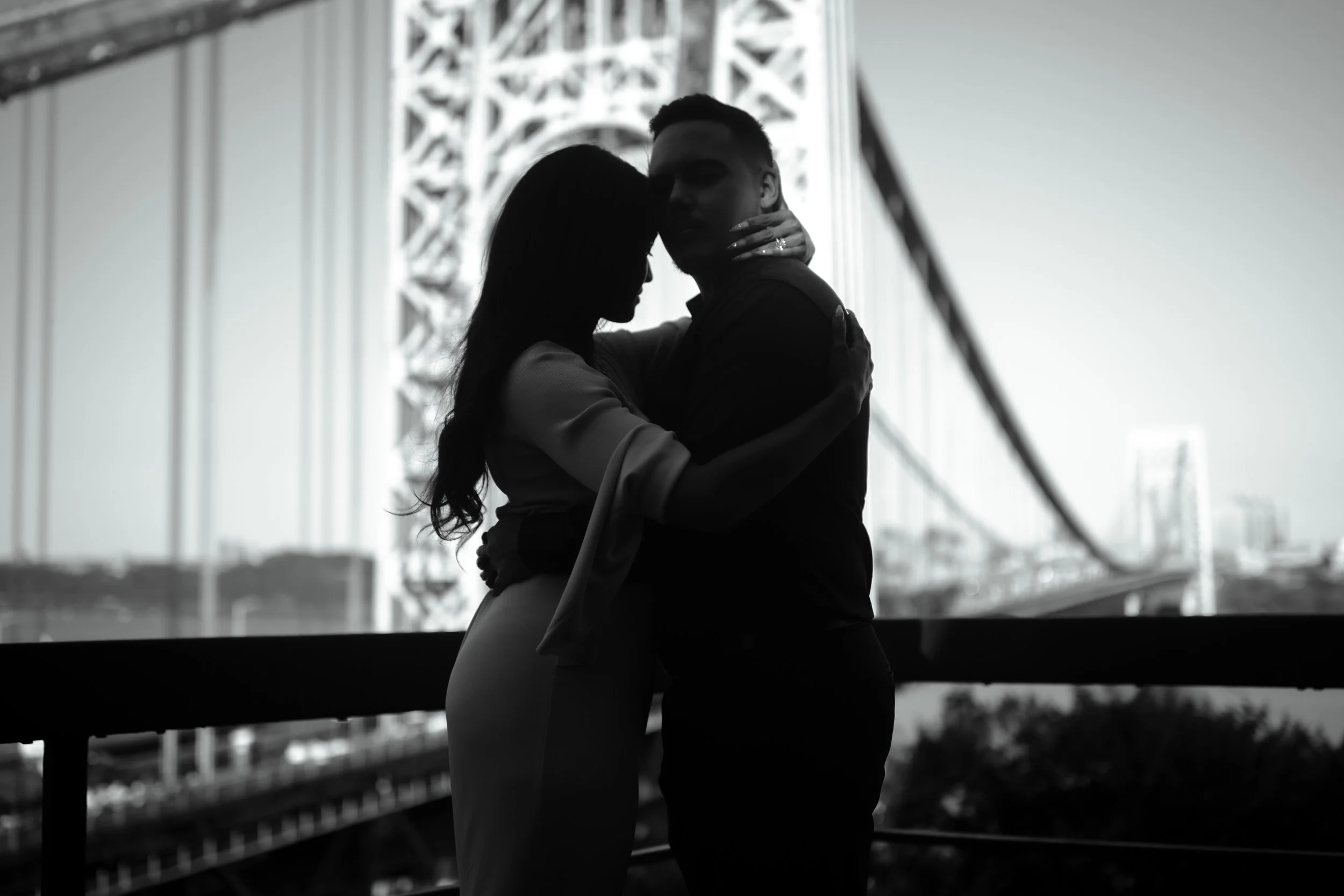 Silhouette of a couple embracing on a bridge at sunset