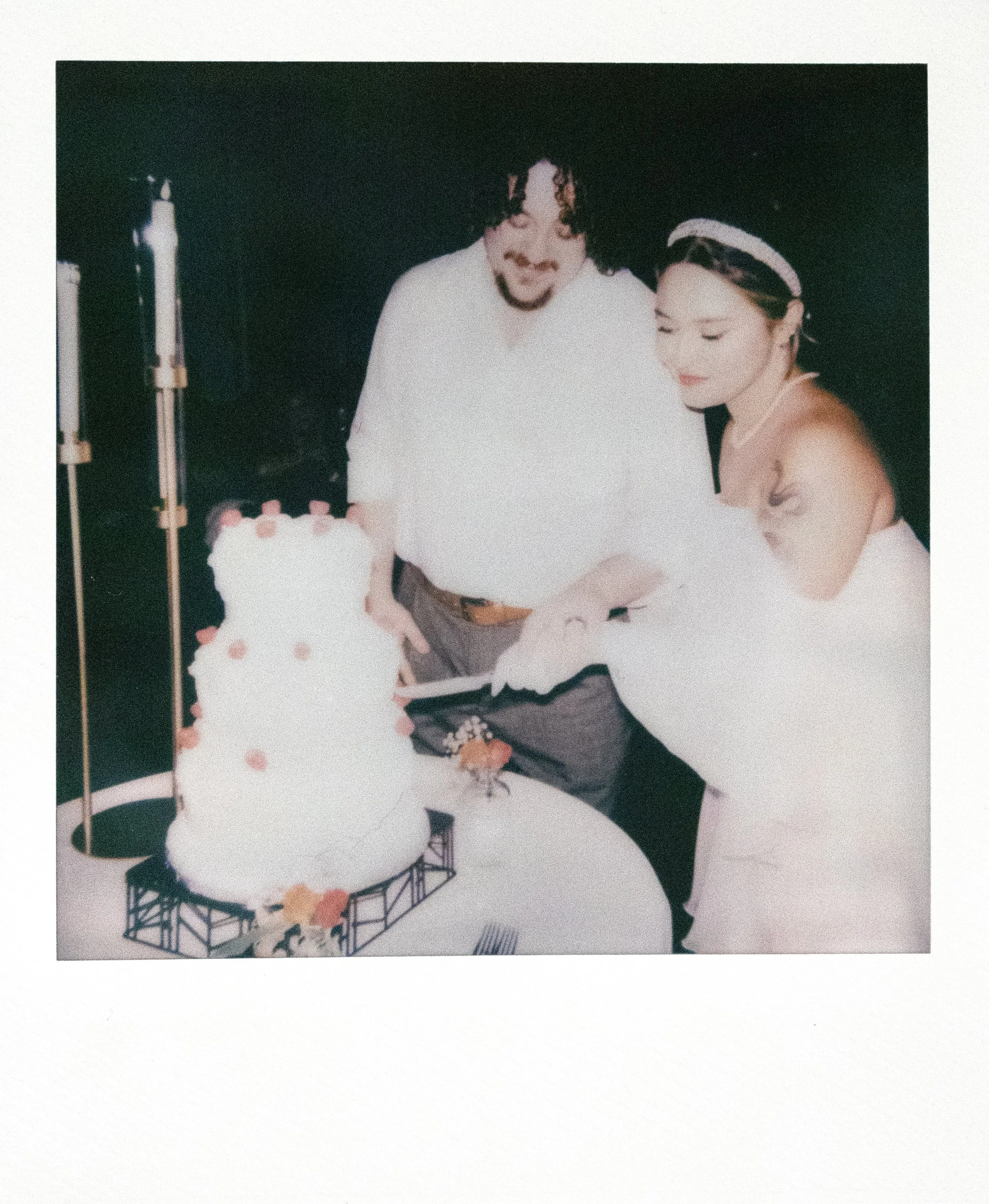 A man and woman cutting a wedding cake at a celebration.