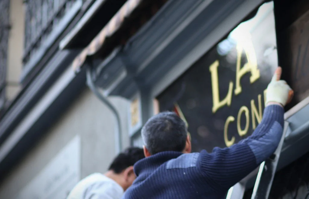 Los carpinteros instalando el rotulo en la caja superior de la fachada.