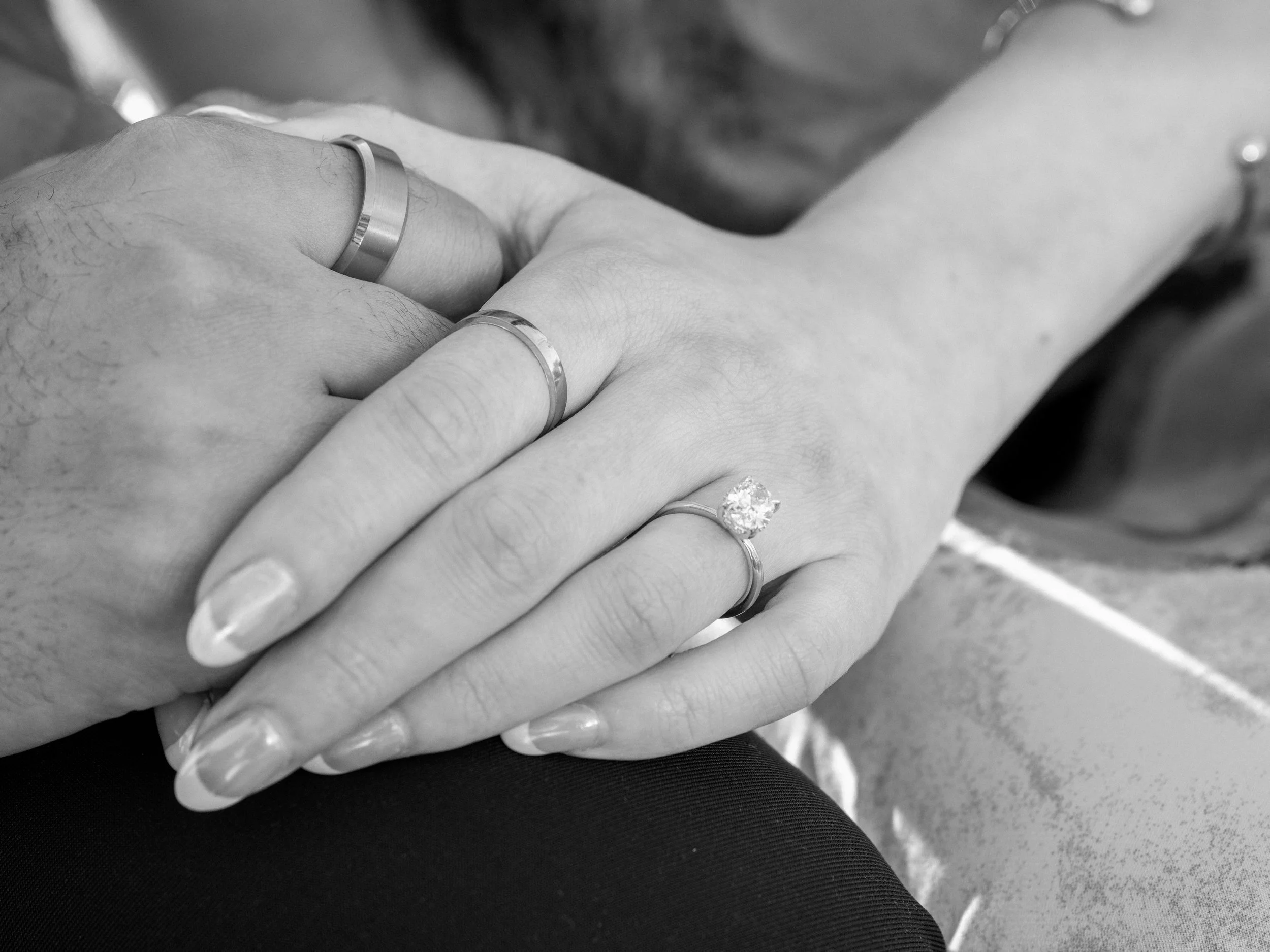 Close-up of two hands holding each other, showing wedding rings on their fingers.