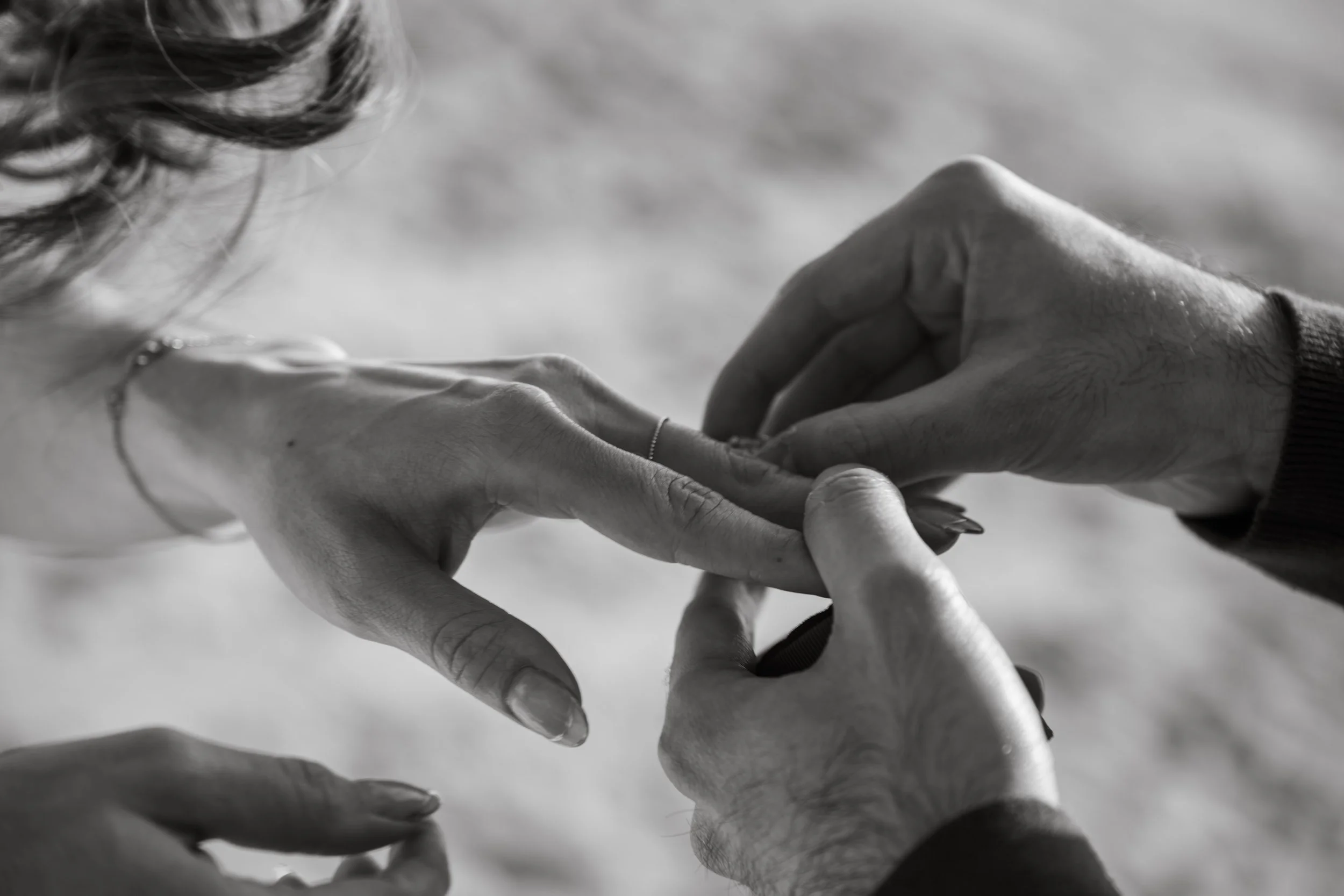 Close-up of two hands gently holding each other, with one hand supporting the other, black and white photograph.