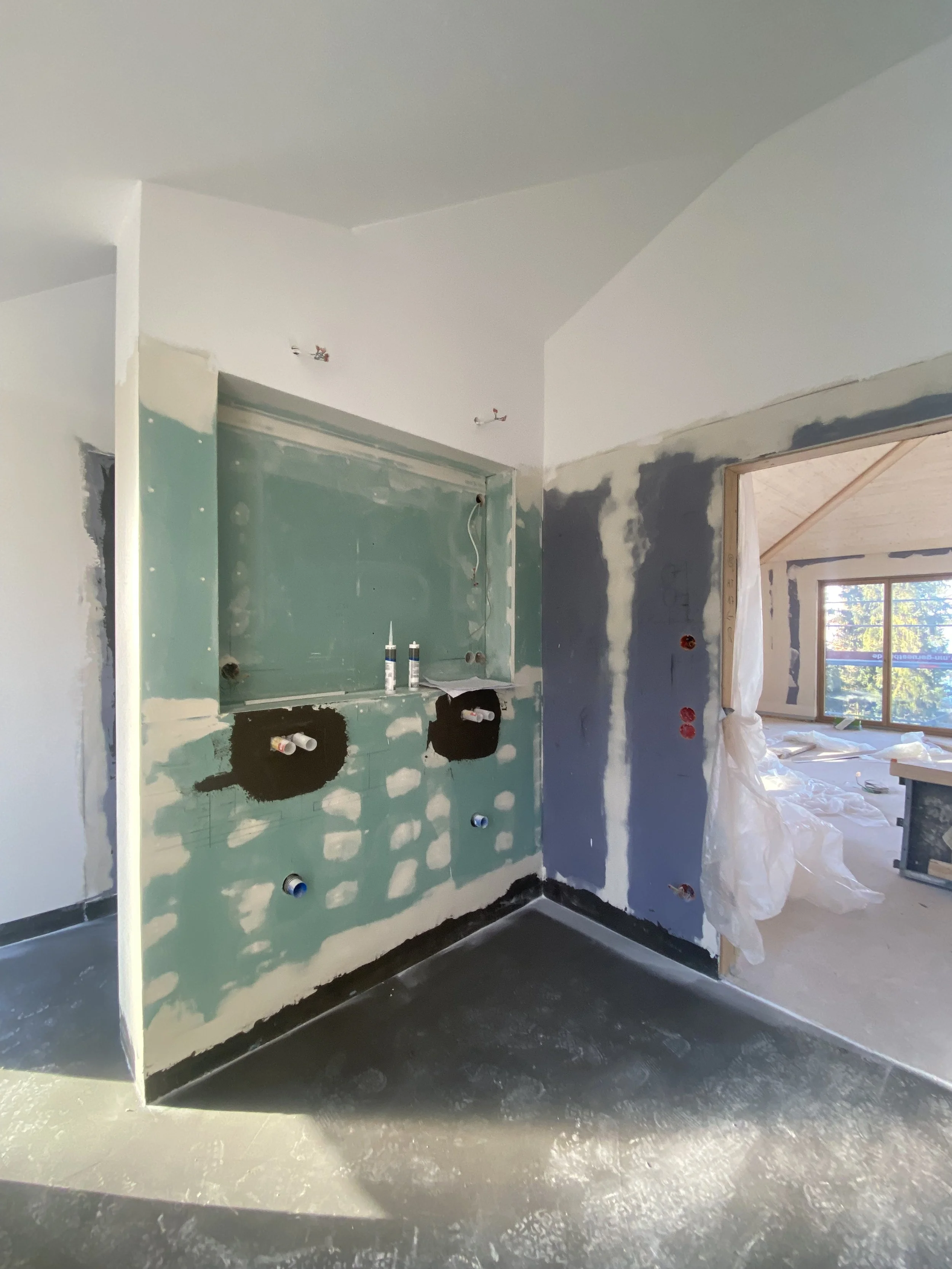 Innenaufnahme eines Hauses unter Baumaßnahmen, noch im Rohbau, mit sichtbaren Wänden und Installationsleitungen.