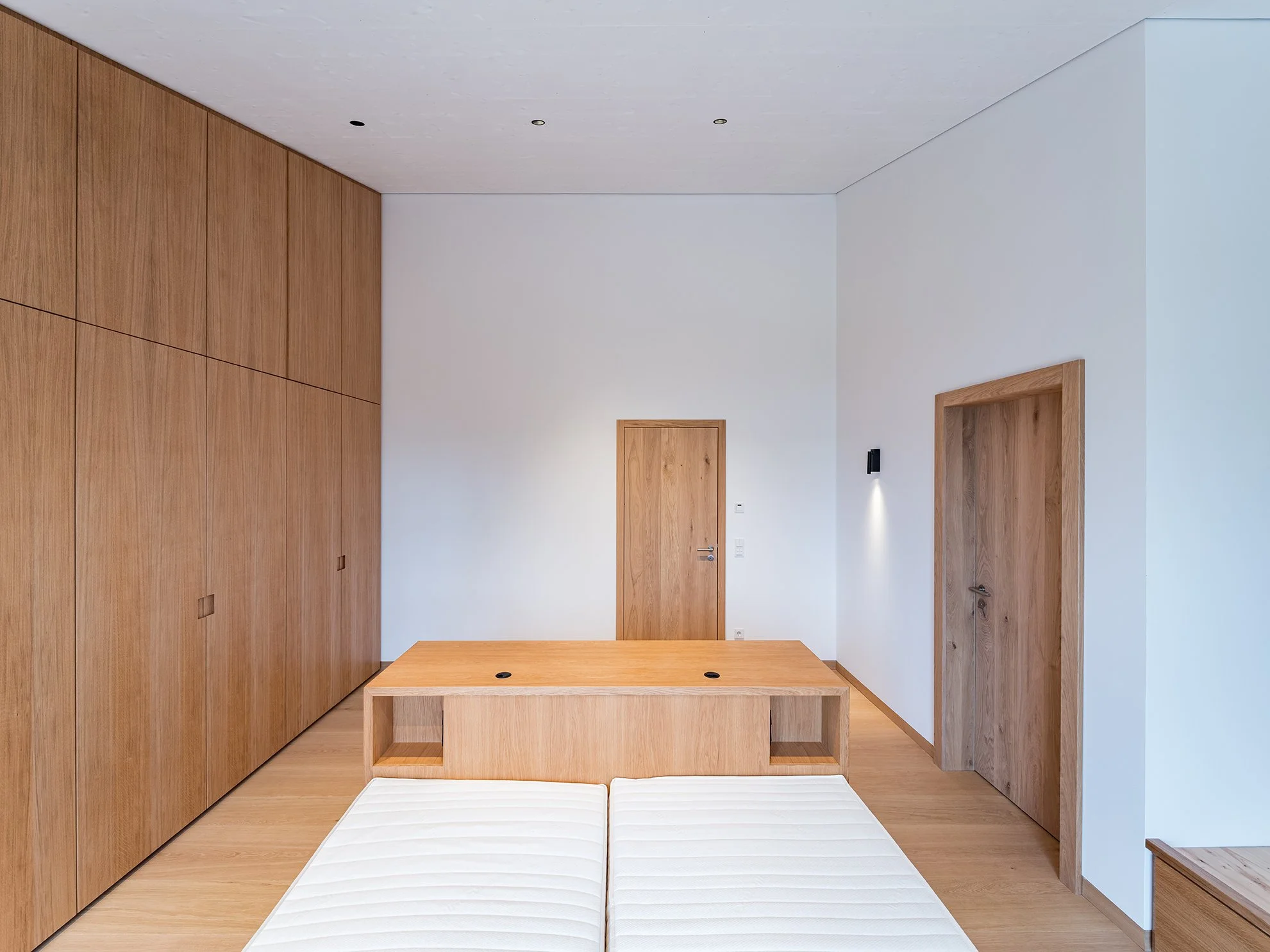 Ein modernes, minimalistisches Schlafzimmer mit Holzmöbeln und weißen Wänden.