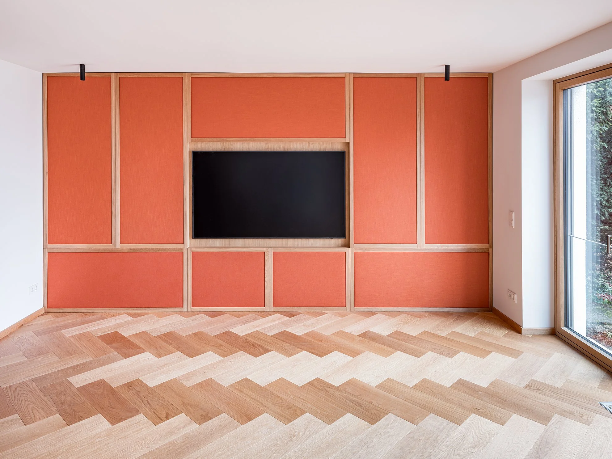 Leeres Wohnzimmer mit rotem Wandpaneel und großem Fenster