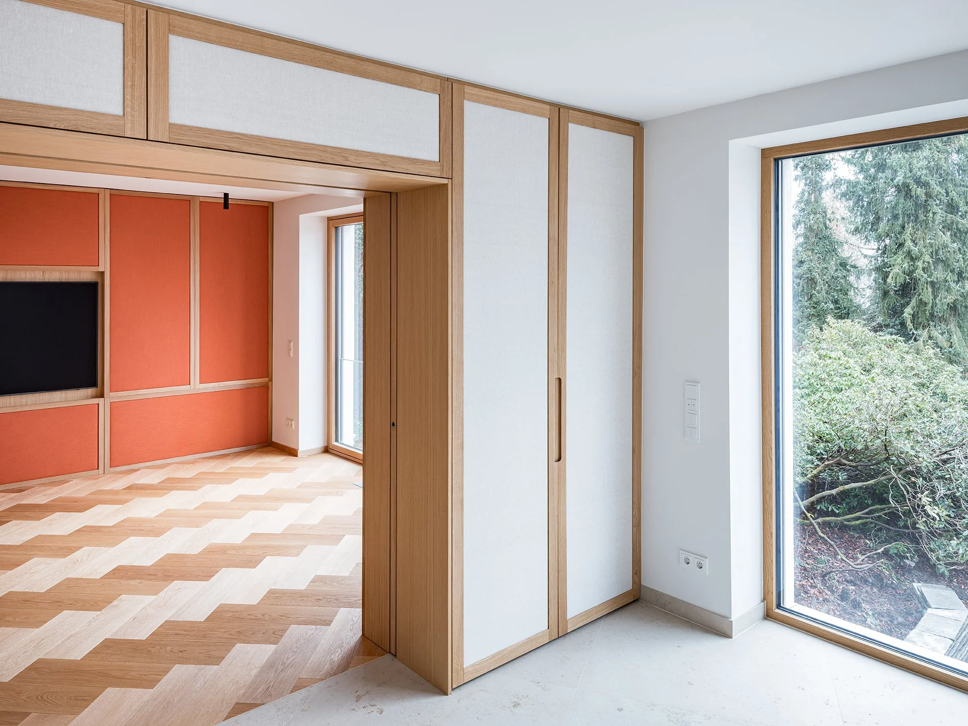 Innenraum eines modernen Hauses mit großen Fenstern, Holztüren und Parkettboden.