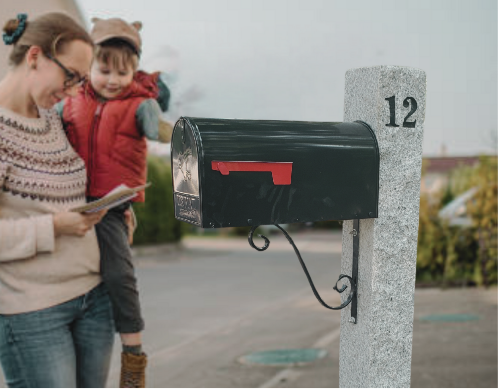 A woman and a child standing near a black mailbox mounted on a concrete post with the number 12, outdoors on a cloudy day.