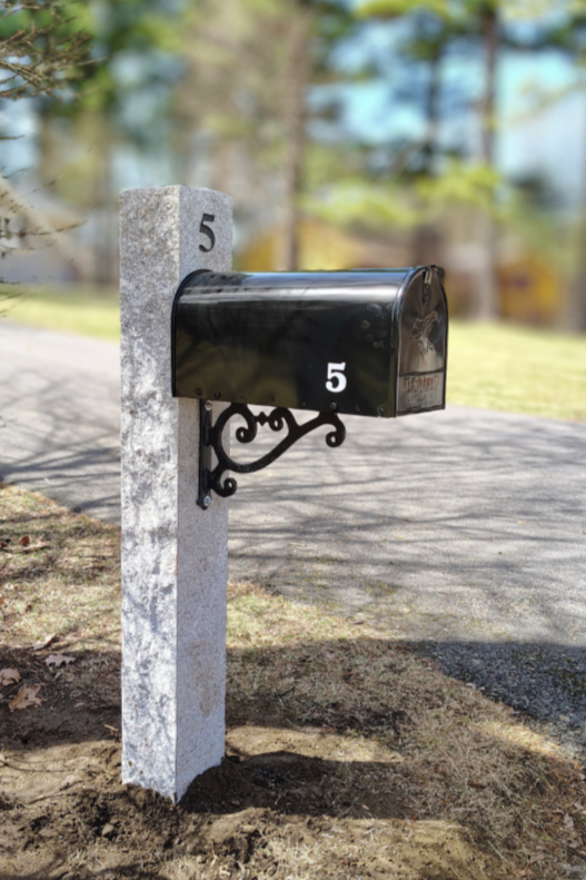 Black mailbox with the number 5 on side and front, mounted on a stone post