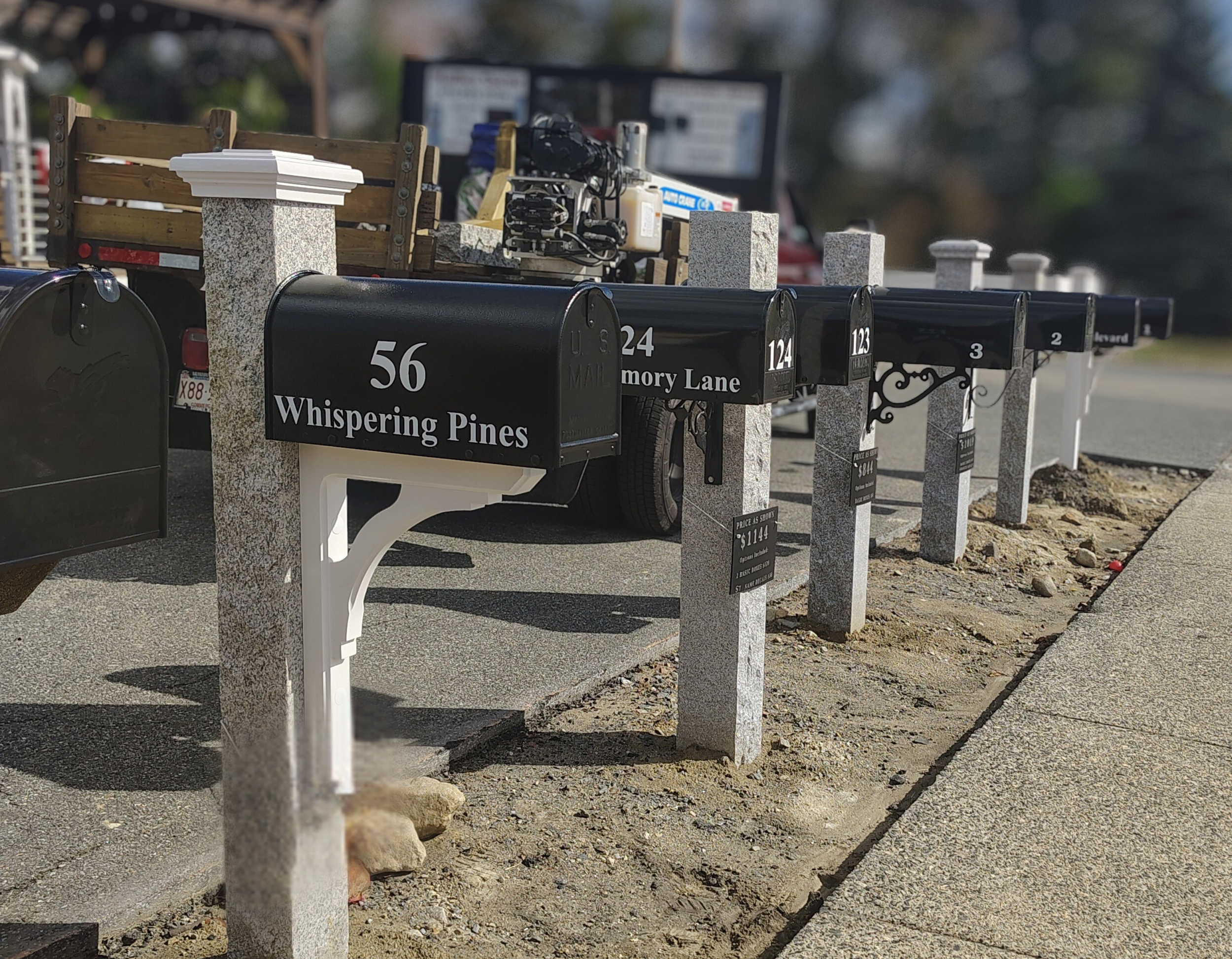 granite mailbox post display at top tier outdoor living in north reading ma. display features five fully installed stone mailbox posts along with one white vinyl post.