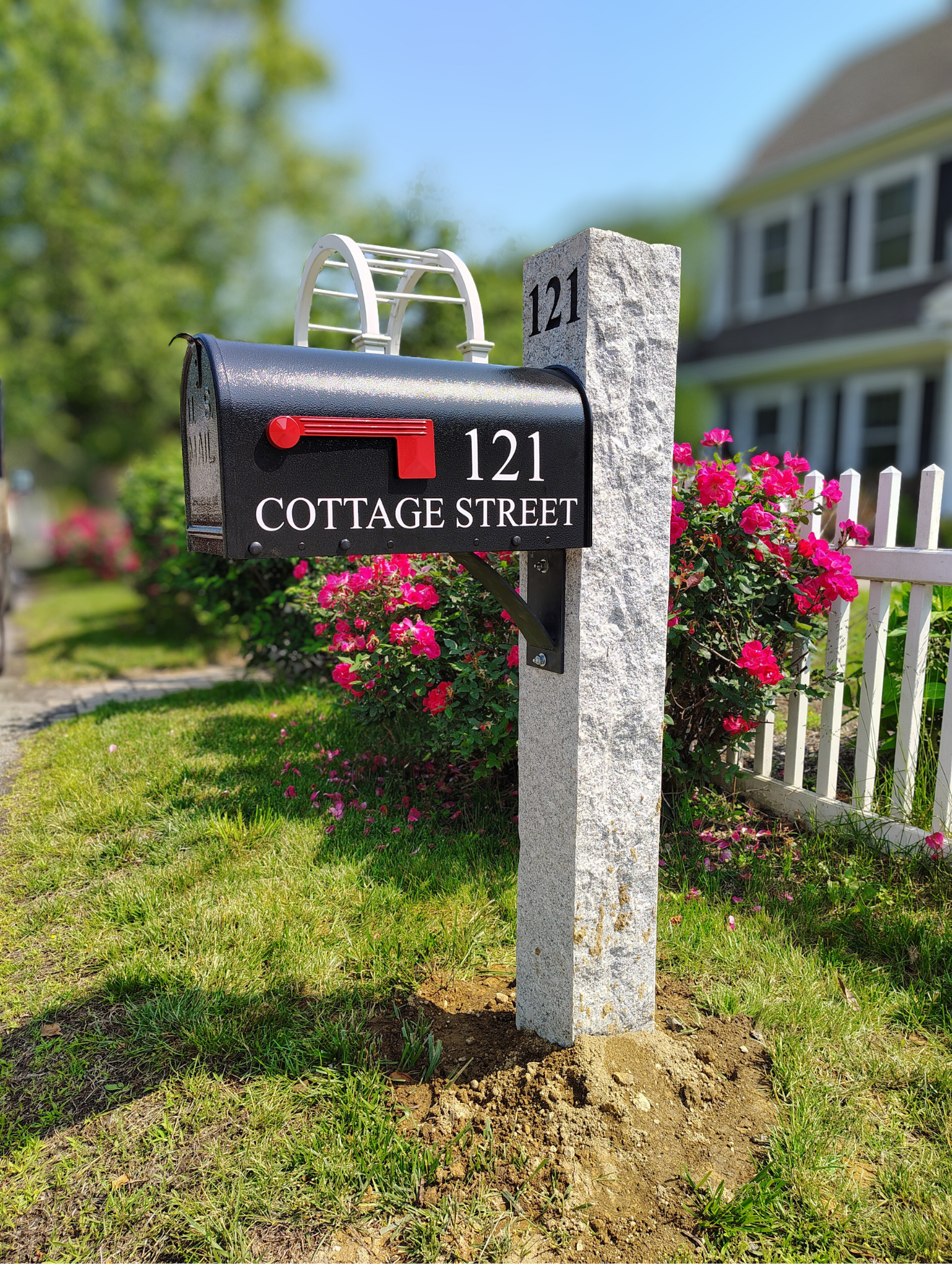 granite mailbox post with bracket, black mailbox, and white address decals
