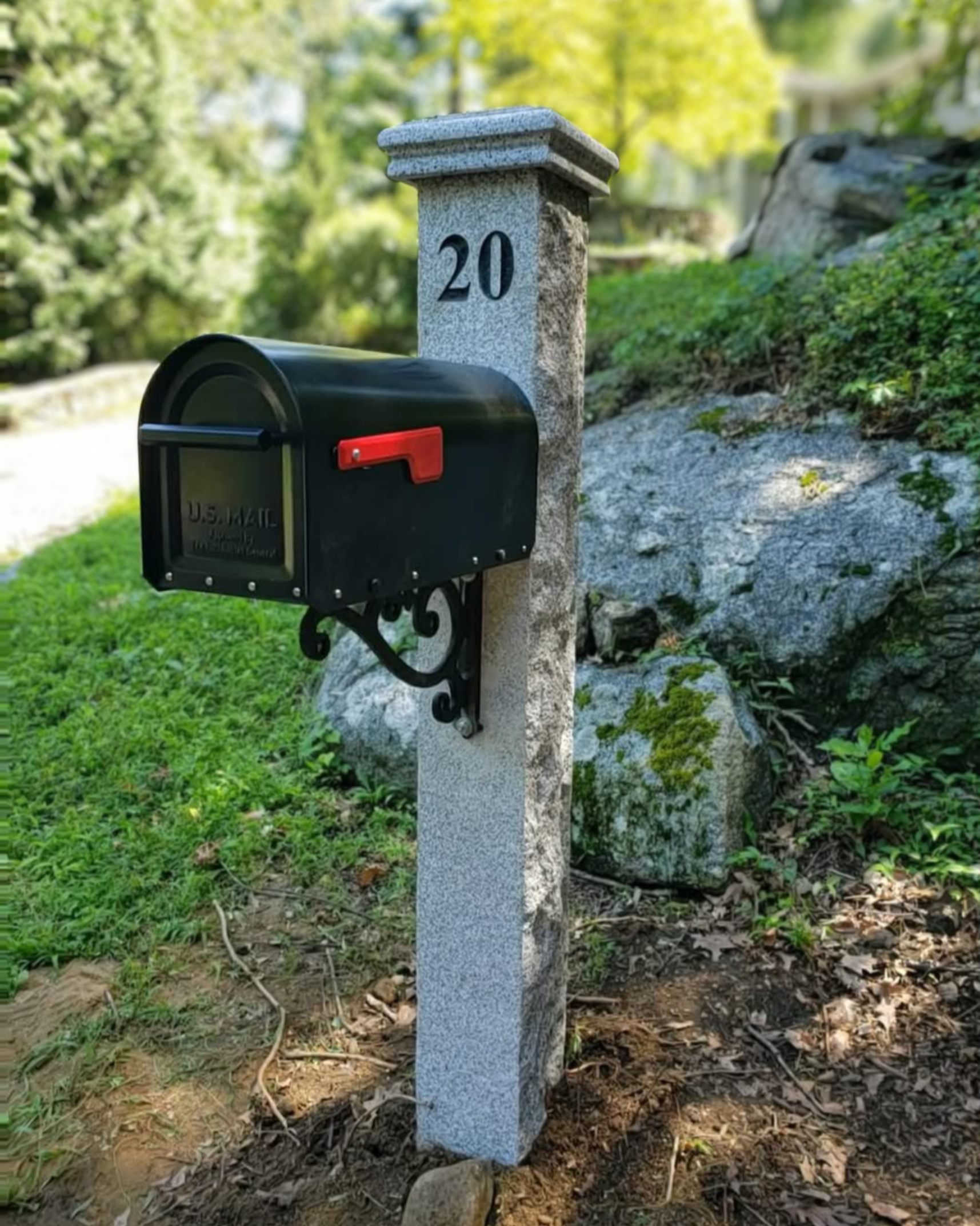 A black mailbox with a red flag mounted on a stone post marked with the number '20' in a green, leafy yard.
