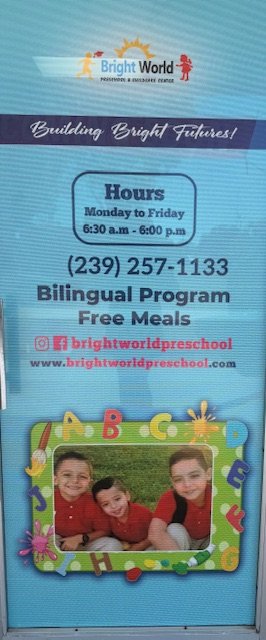 Bright World preschool door sign with hours, contact, and program info, featuring a photo of three children inside a colorful alphabet-themed frame.