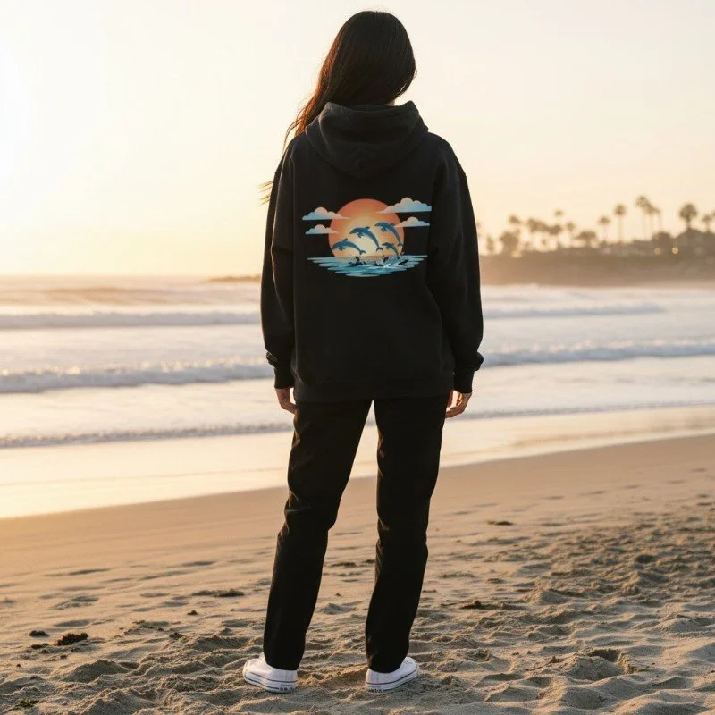 Person wearing black hoodie with dolphins swimming at sunset graphic inspired by Western Australia ocean.