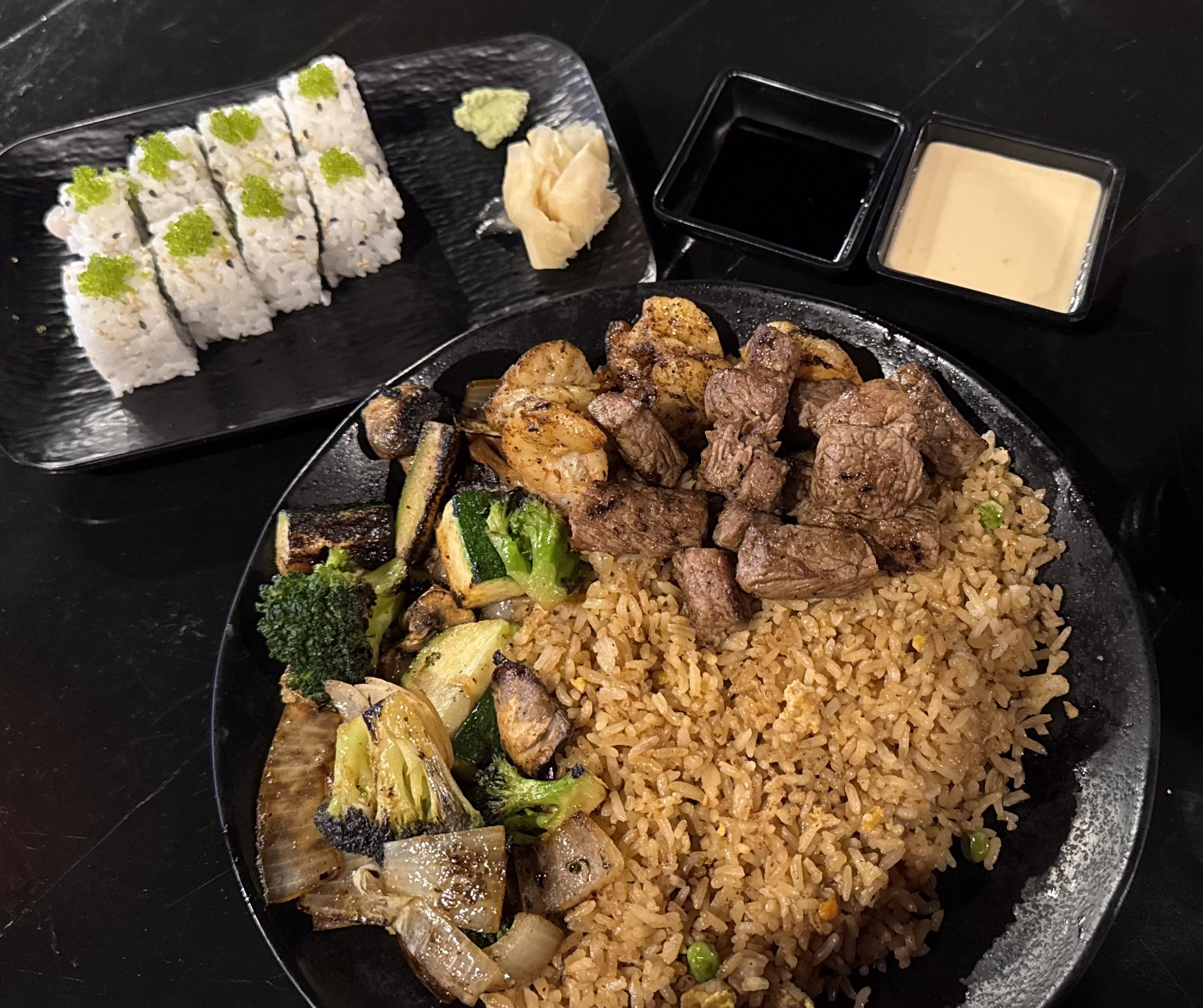 Hibachi filet mignon steak and shrimp with fried rice, yum yum sauce, vegetables, and sushi roll