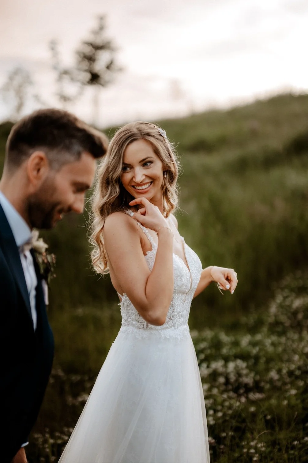 Ein lächelndes Brautpaar bei einer Hochzeit beim Haus Landscheid in Burscheid, die Braut trägt ein weißes Hochzeitskleid mit Spitzendetails, der Bräutigam trägt einen dunklen Anzug mit Fliege. Zuvor hatte das Brautpaar die Trauung in Köln.