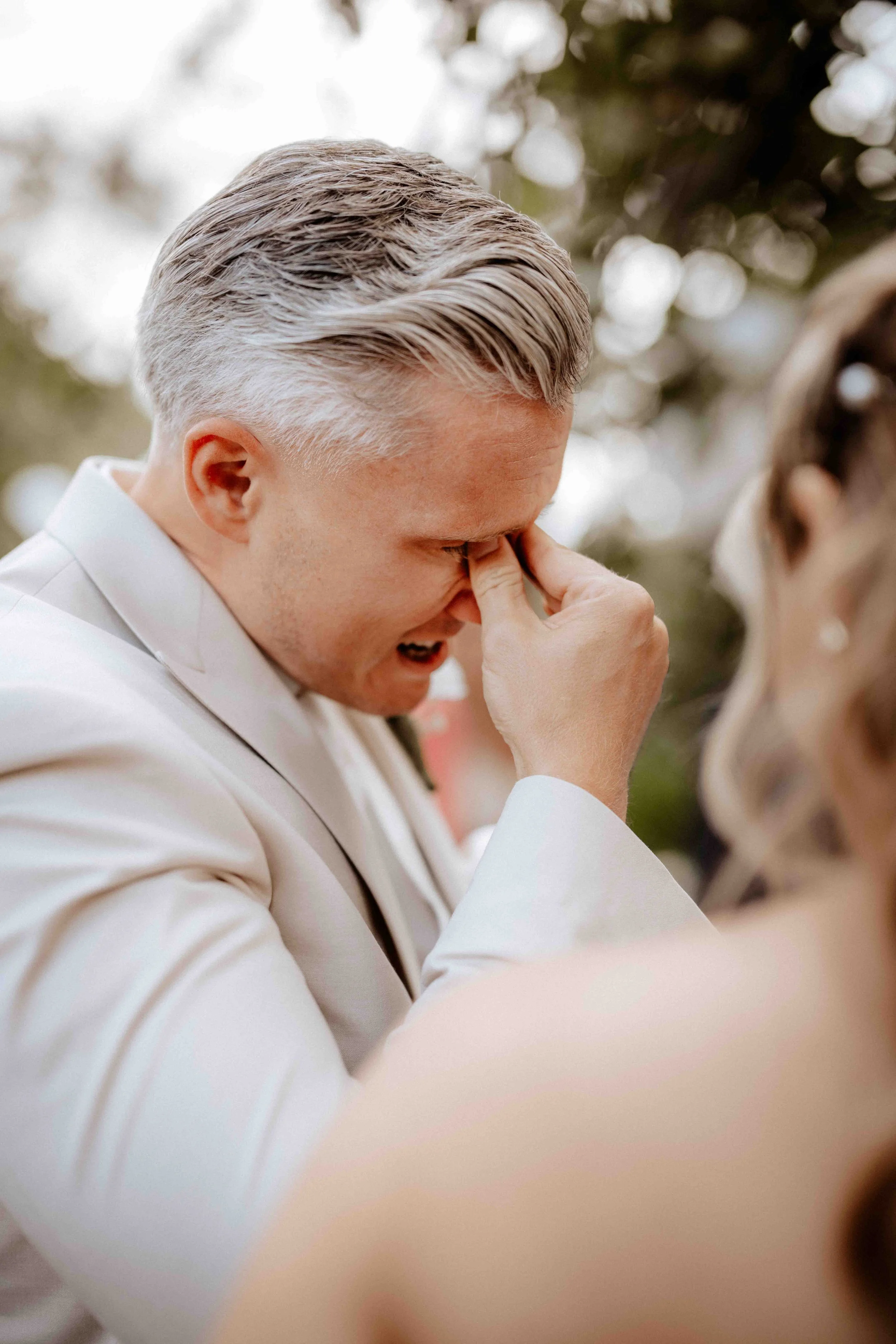 Ein Mann in weißem Anzug, der vor einem emotionalen Moment die Nase putzt und Tränen vergißt. Die Hochzeit findet in Köln Rodenkirchen statt. 