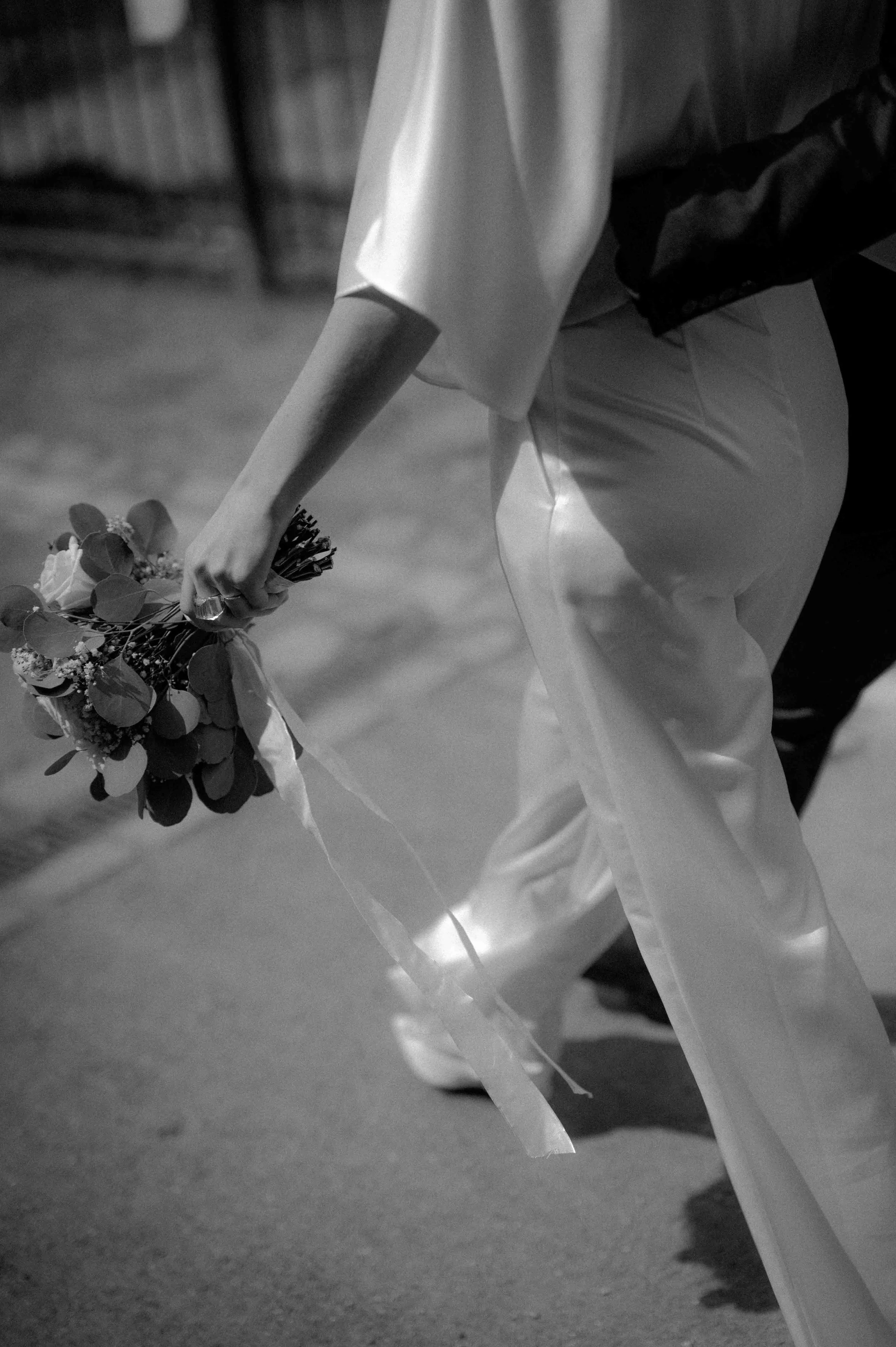 Schwarz-weiß-Foto einer Person, die einen Blumenstrauß hält, bei einer Veranstaltung, wahrscheinlich eine Hochzeit, mit einem leichten Blick auf den Boden. Die Hochzeit findet in Ratingen beim Haus Cromford in der Nähe von Düsseldorf statt.