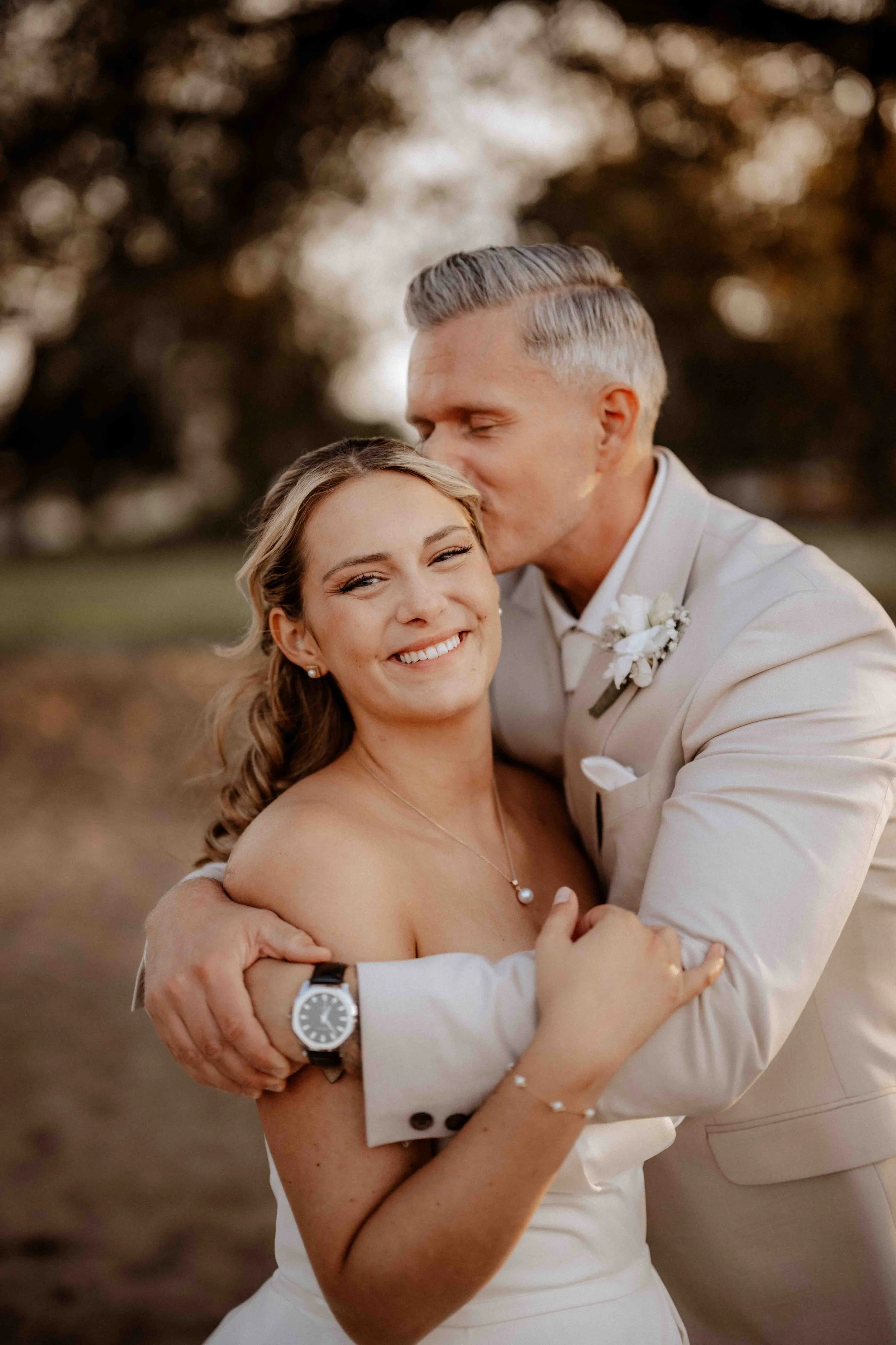 Die Hochzeit findet in Köln Rodenkirchen statt. Ein glückliches Brautpaar, der Mann küsst die Braut auf die Stirn, im Freien bei Sonnenuntergang.