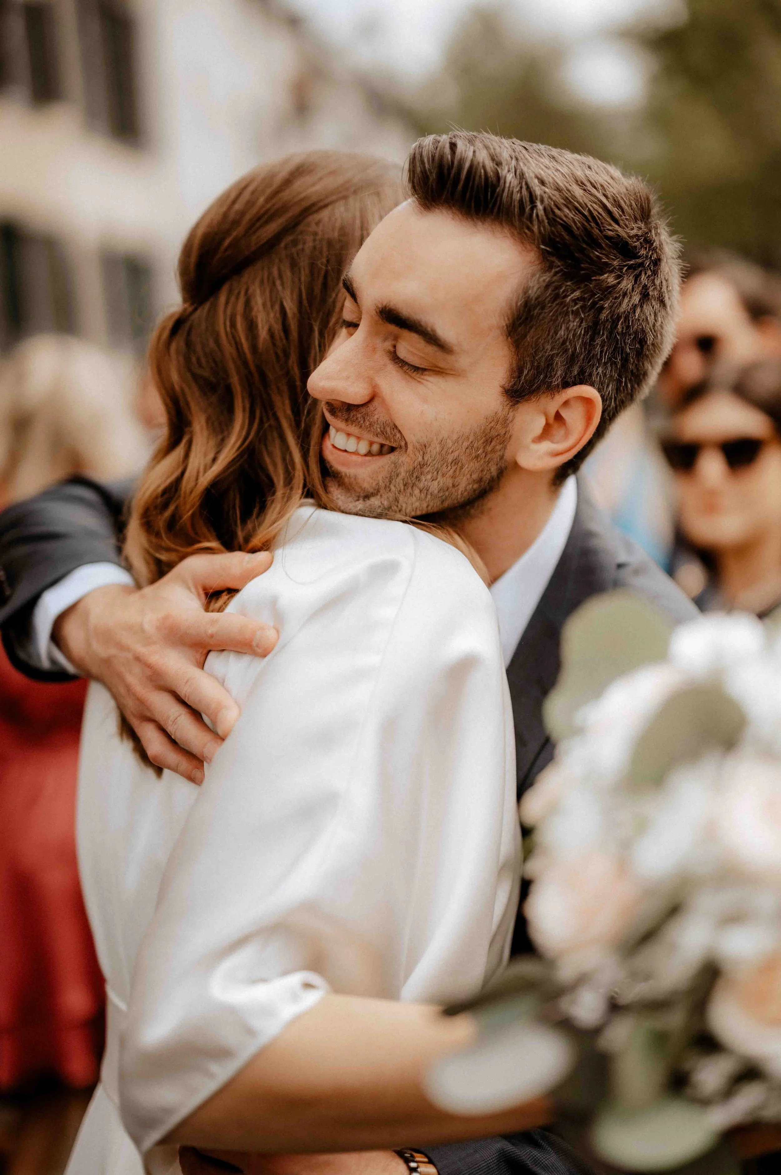 Ein Mann und eine Frau umarmen sich bei einer Feier, beide lächeln glücklich. Die Hochzeit findet in Ratingen bei Düsseldorf statt. 