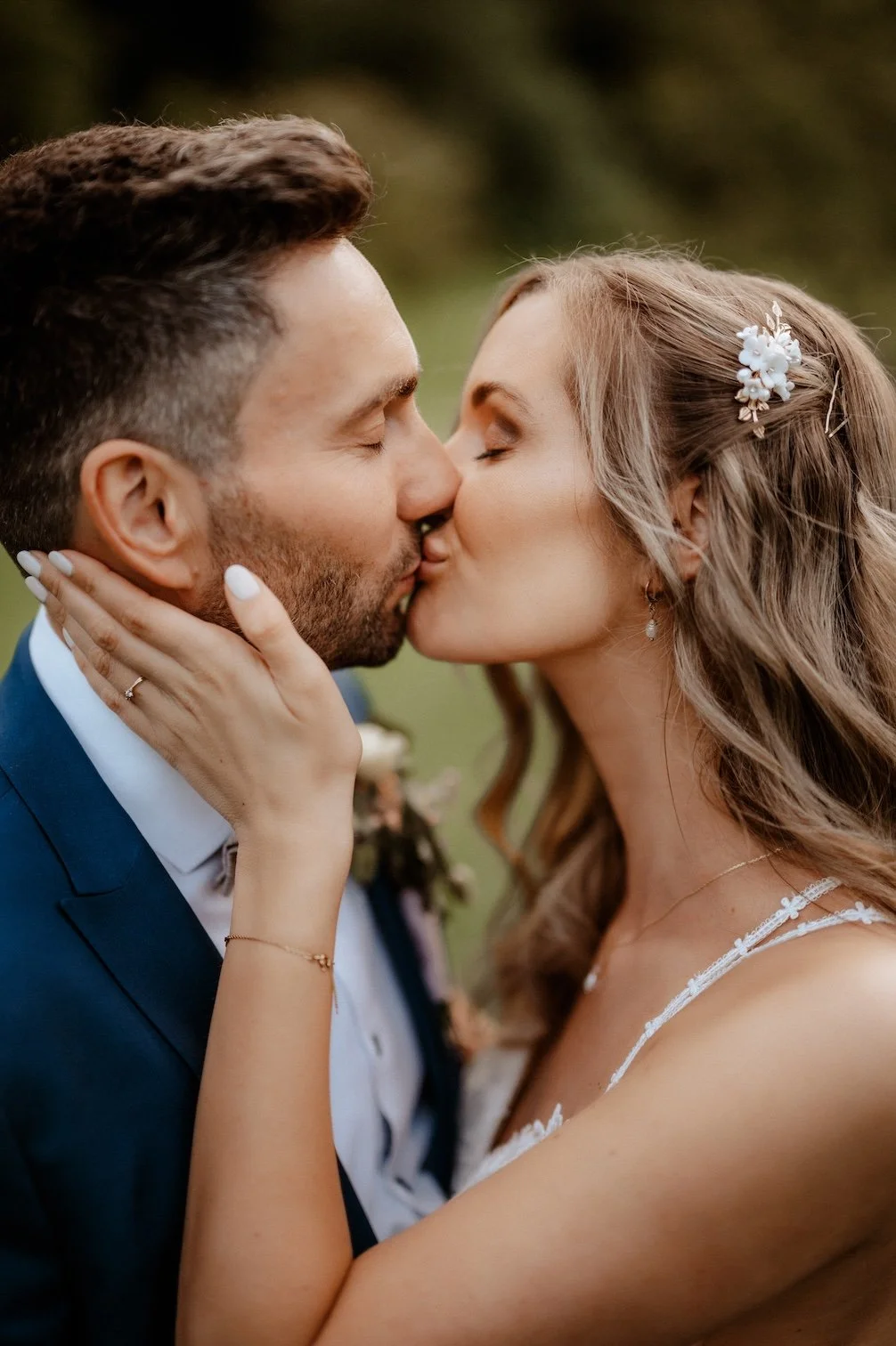 Ein verliebtes Paar küsst sich bei einer Hochzeit im Freien, die Frau hält den Mann im Gesicht, während er einen Kuss erwidert. Die Hochzeit findet in Düsseldorf, Nähe Köln statt. 