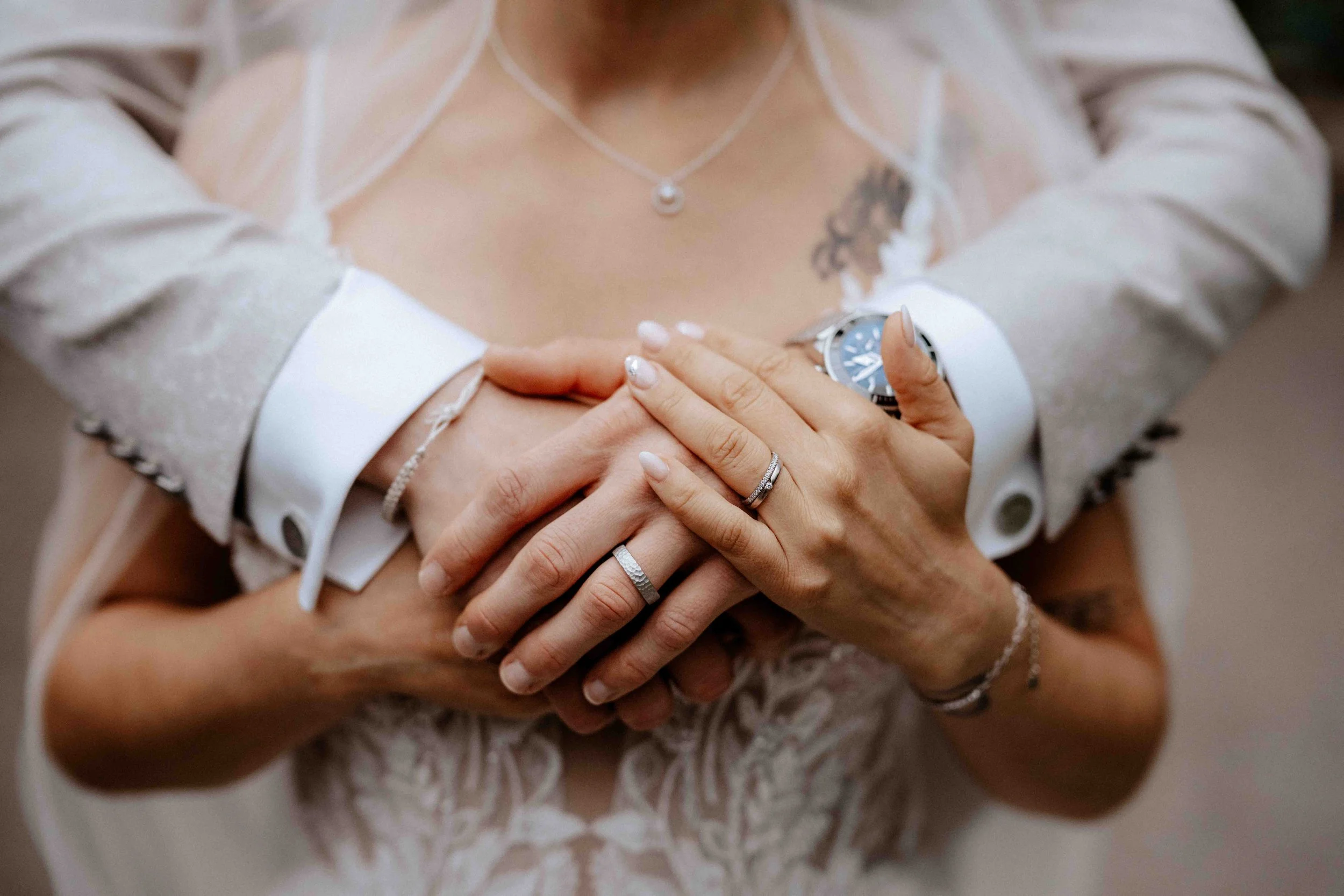 Ein Brautpaar hält Händchen, sichtbar sind Eheringe, Schmuck und Uhren. Die Hochzeit findet in Düsseldorf, Nähe Köln statt. 