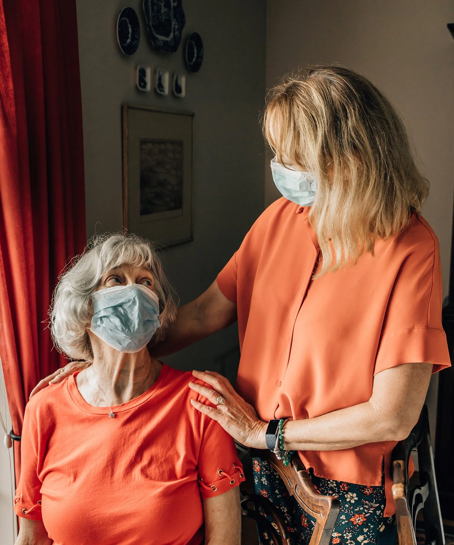 Caregiver wearing a mask checking in with an older adult client wearing a mask.