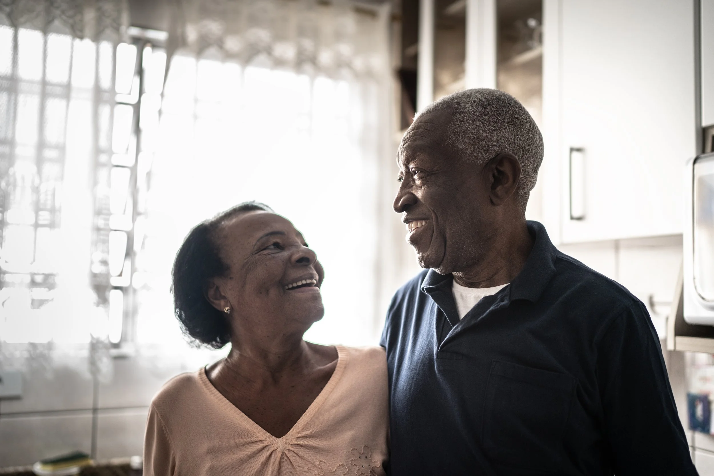Two elderly adults smiling at each other.