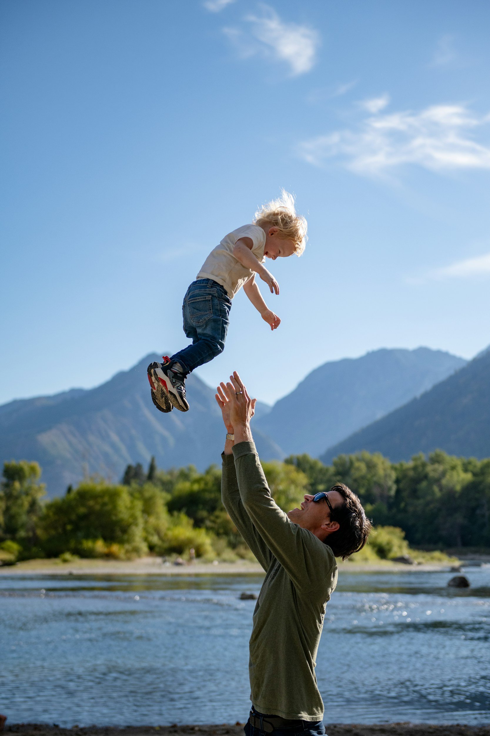 man throwing a child in the air in a mountain scene