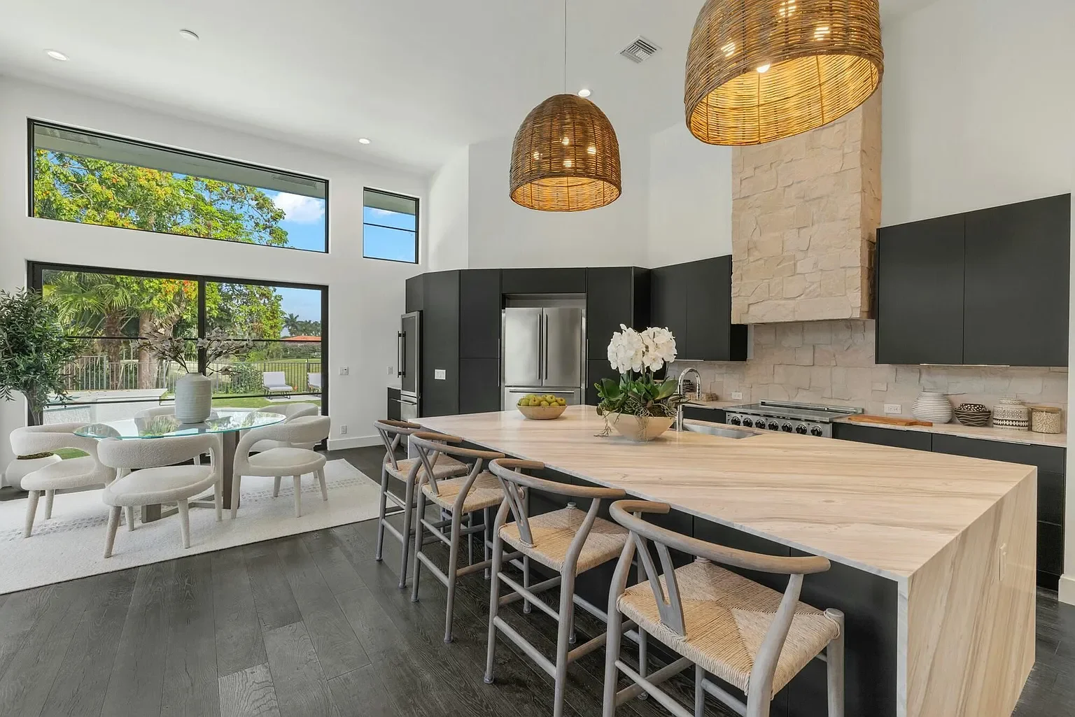 Modern kitchen with white cabinets, marble countertops, stainless steel appliances, and light wood flooring.