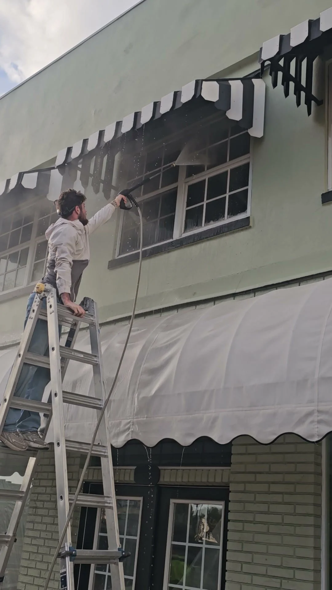 Chris pressure washing a commercial storefront in Highlands County, removing years of built-up grime from the stucco and windows.