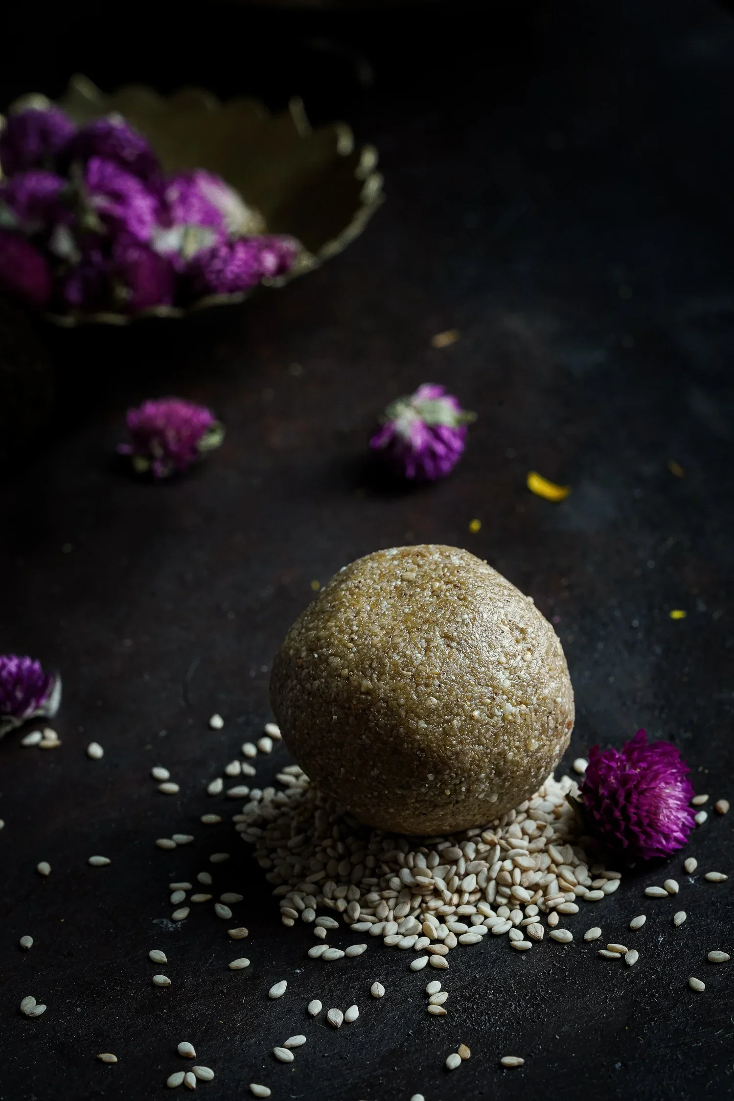 a circular stone with seeds and purple flowers on a black background