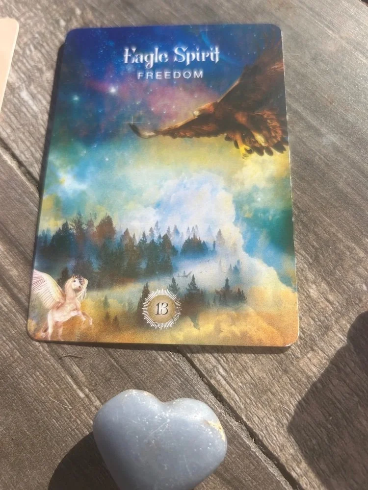 oracle card with an eagle and unicorn, with forested landscape and an angelite heart crystal