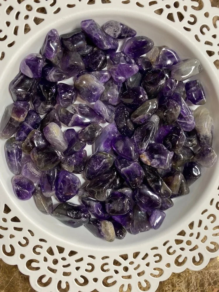 small white container of tumbled amethyst crystals