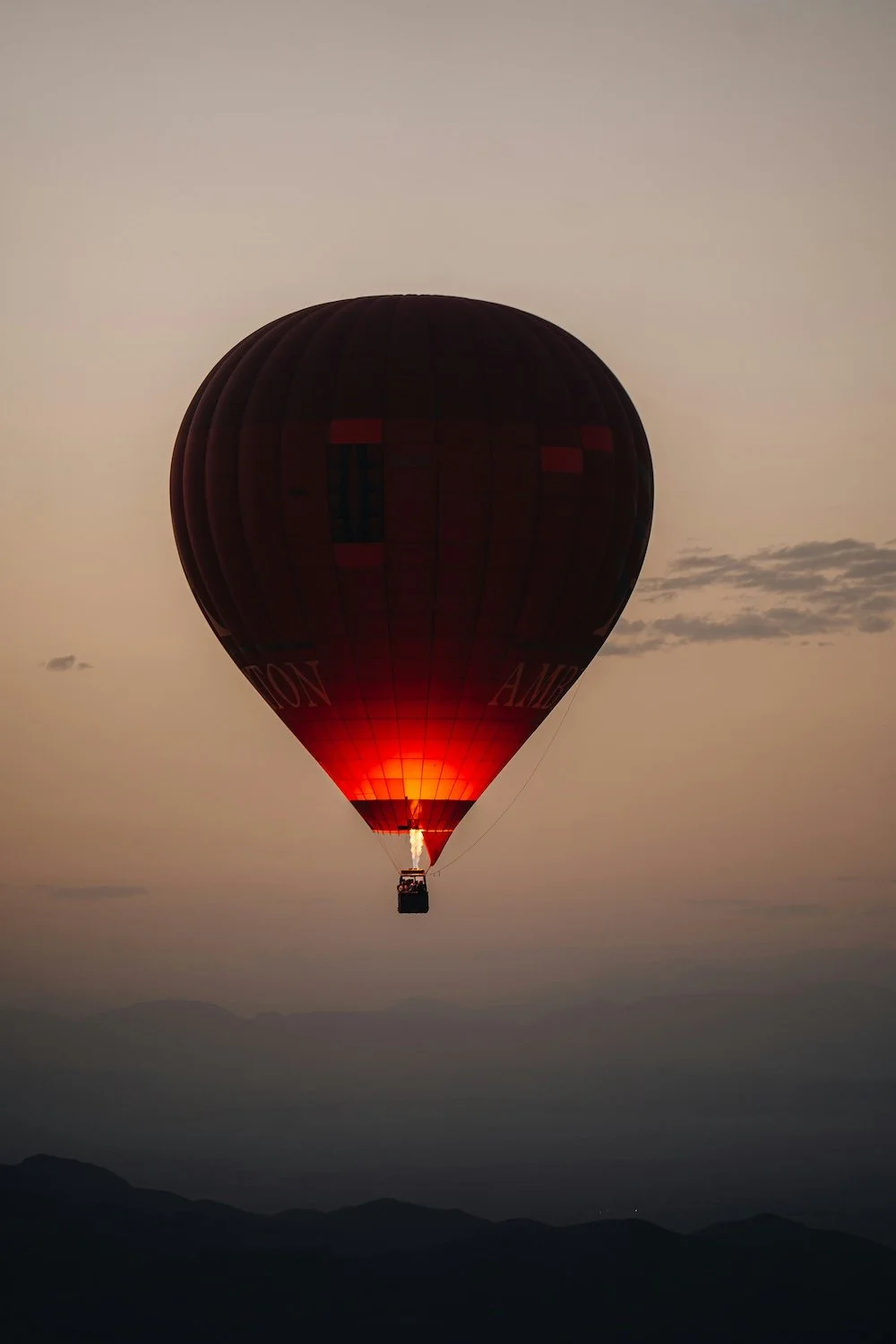 Silhouette of hot air balloon lit from below; dusk sky in background