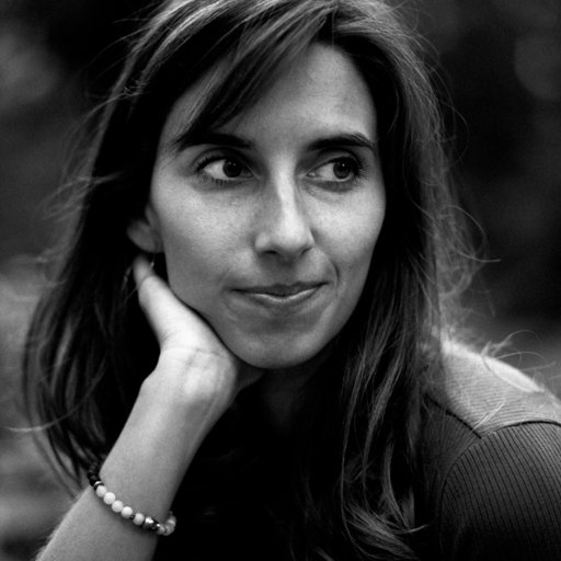 Portrait en noir et blanc d'une femme avec les cheveux longs, les yeux regardant sur le côté, la main tenant son visage, portant un bracelet à son poignet.