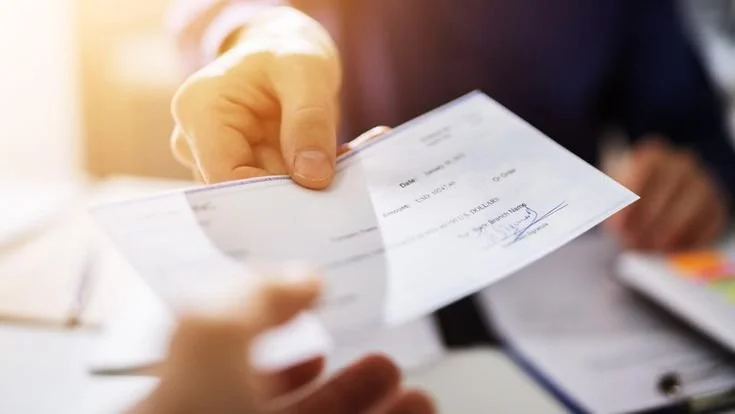 A person is handing a check to another person.