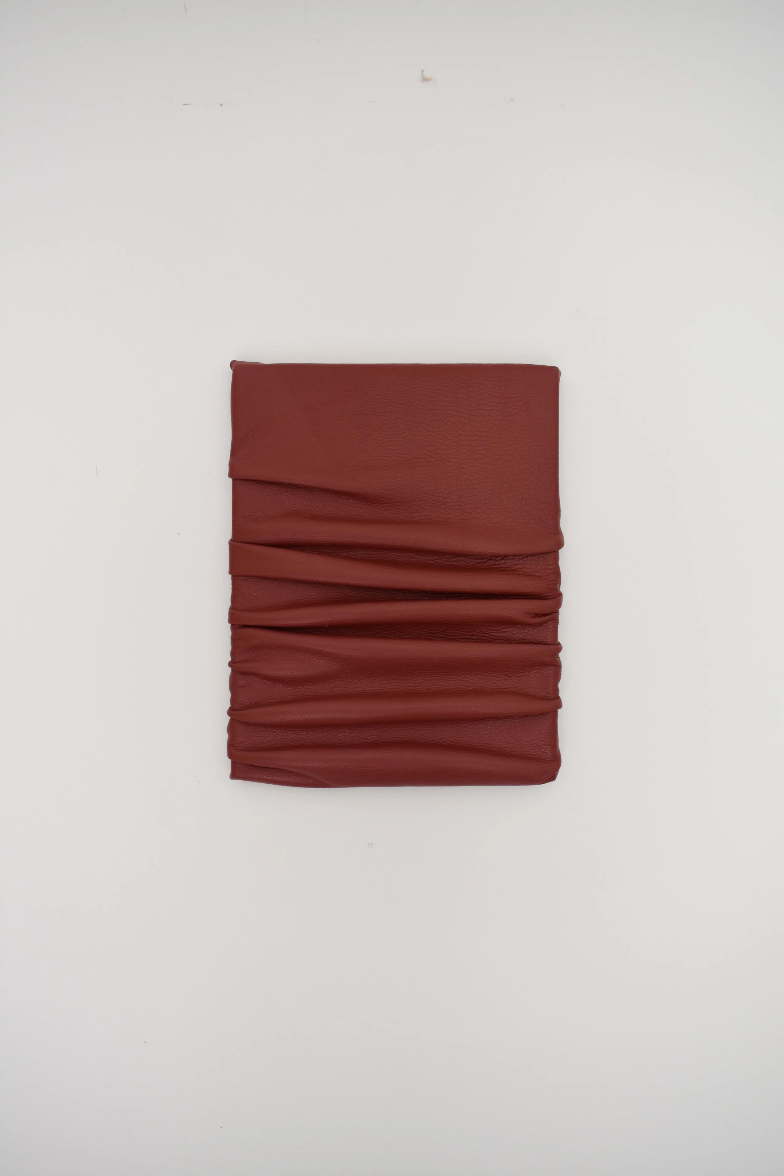 A folded red leather wallet or clutch with a textured surface placed on a white background.