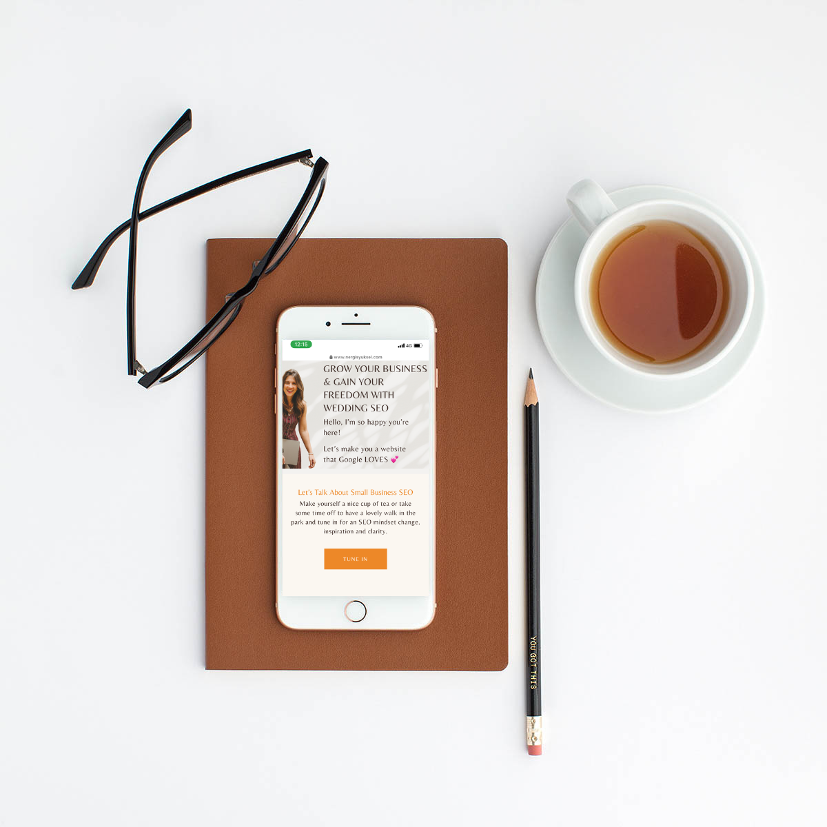 Iphone laid flat on table next to cup of tea and glasses. Nergis' link in bio page is open on iphone screen