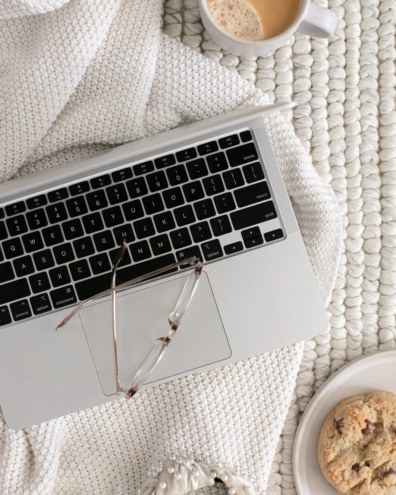 Laptop placed on a rug with coffee and biscuit