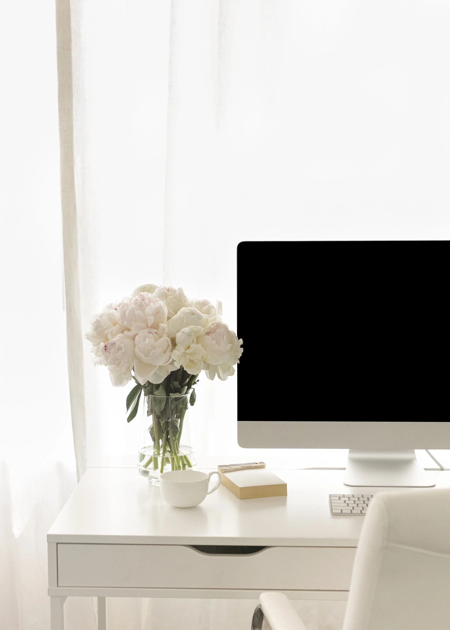 Desktop screen on a white desk with white flowers to symbolise seo friendly web design