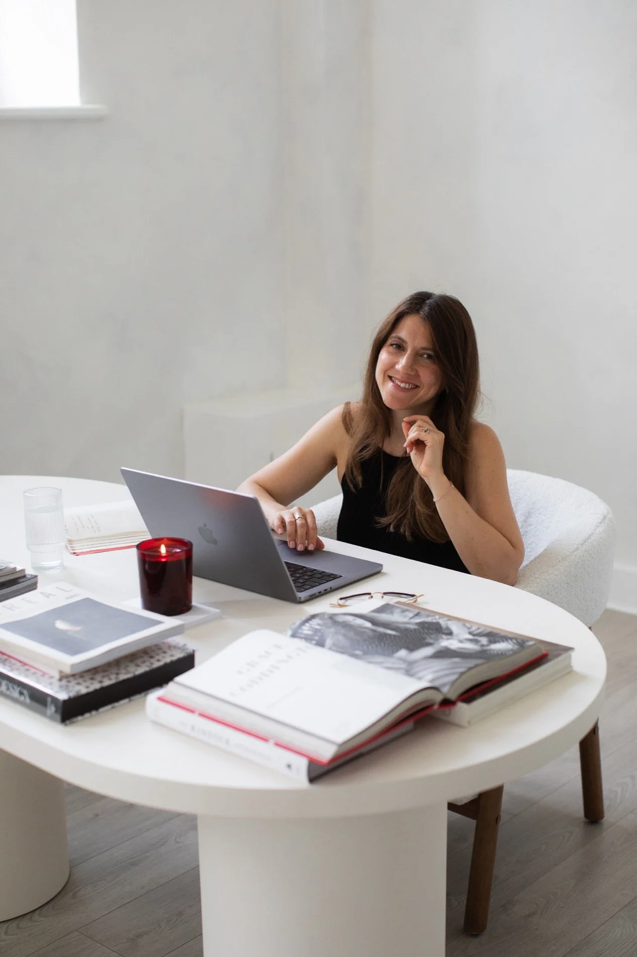 Wedding SEO coach and strategist Nergis smiling at a camera while sitting behind her laptop